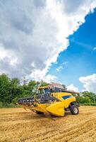 Agriculture machine harvesting crop in fields. Special technic in action. Agricultural technic in field. Heavy machinery. Blue sky above field. photo