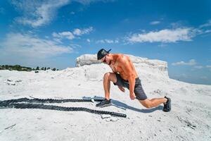 Brutal strong bodybuilder posing outdoor. Photoshoot in a quarry. Outdoor sports concept. Posing with ropes. White landscape. photo
