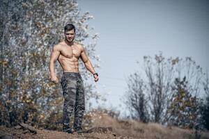 Bodybuilder posing shirtless outdor. Trees background. Perfect body. photo