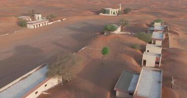 ein Drohne fliegt durch ein Dorf bedeckt mit Sand im das Mitte von das Wüste video