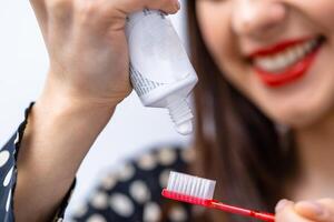 Toothbrush and toothpaste on it on front view. Girl on the blurred background. photo