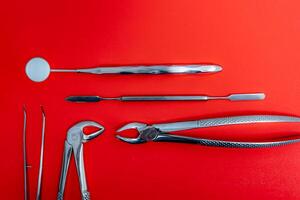 Art photo for dental concept. Set of metal dental instruments on red background.