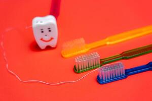 Teeth toy dental in a smiling mood with tooth brushes on red background. Colorful tooth brushes. photo