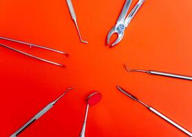 Dental set, mirror, probe. Concept care. Instruments isolated on red background. photo