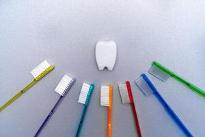Colorful tooth brushes lay around tooth floss in tooth toy shape. photo
