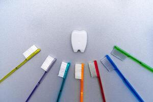 Colorful tooth brushes lay around tooth floss in tooth toy shape. photo