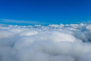 Light clouds seen from airplane. Blue endless sky above fluffy clouds. photo