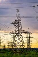 Electrical transmission lines over green grass. Power lines in the beautiful landscape of nature. Selective focus. photo