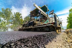 Selective focus on newly laid asphalt. Heavy special technic for flattering asphalt at road. Construction site. photo