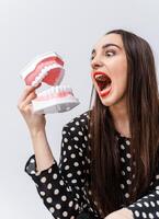 Funny girl toing with dental jaw on white background. Opened plastic jaw. Roaring girl with funny emotions. photo