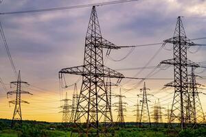 Electricity pylons and high-voltage power lines on the green grass. Power plant. Electrical power grid. View from below. photo