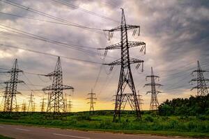 Electricity pylons and high-voltage power lines on the green grass. Power plant. Electrical power grid. View from below. photo