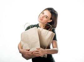 Pretty young woman with paper shopping bags. White background. Happy smiling lady hugging brown paper bags. photo