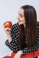 linda mujer con rojo labios. mujer mirando a manzana en su manos. facial expresiones foto