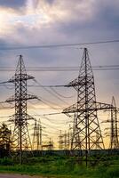 Electricity pylons bearing the power supply across a rural landscape during sunset. Selective focus. photo