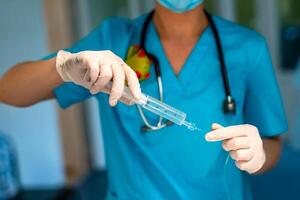 un médico sorteos un medicina dentro un jeringuilla. enfermedad tratamiento. drogas en contra infeccioso enfermedades. manos en guantes sostener un cuentagotas. concepto - tratamiento con medicamentos foto