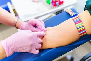 A nurse takes a blood sample from a patient in a doctors office. photo