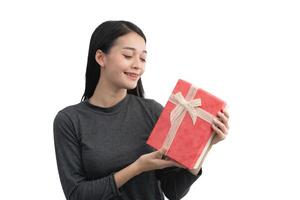 un mujer es participación un rojo presente con un blanco cinta. ella es sonriente y ella es contento. aislado en blanco antecedentes. foto