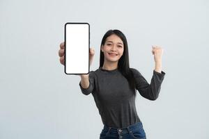 A woman is holding a cell phone with a white background. She is smiling and she is happy. Isolated on white background. photo