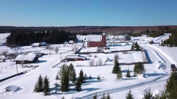 oben Aussicht von klein Dorf mit Hütten im Winter. Clip. klein Dorf im bewaldet Bereich auf sonnig Winter Tag. Fernbedienung Dorf mit groß Backstein Haus video