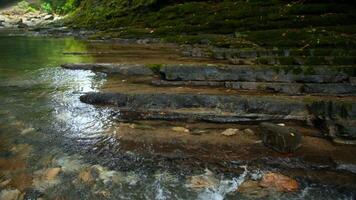 Clear stream running through stone boulders. Creative. Calm river flowing on stone bottom in slow motion. video
