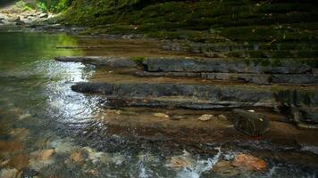 Clear stream running through stone boulders. Creative. Calm river flowing on stone bottom in slow motion. video