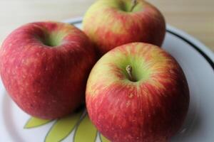 three apples on a plate photo