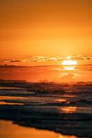 un persona caminando en el playa a puesta de sol foto