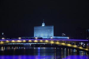 un puente terminado un río a noche con un edificio en el antecedentes foto