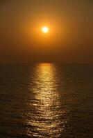 un puesta de sol terminado el Oceano con un barco en el distancia foto