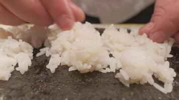 Chief lays out boiled rice on nori sheets. video