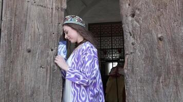 A young woman with long hair in a short white dress and an oriental robe against the background of a wooden gate video