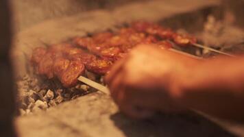 A man's hand flips skewers with barbecue roasting on the grill video