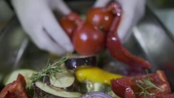 un guantes blancos cocinero revuelve vegetales cortar dentro piezas en un envase con su manos video