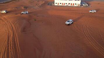 dubai, uae - 1 14 2023. en Drönare flugor över en vit sUV körning genom de sand sanddyner av de öken- video