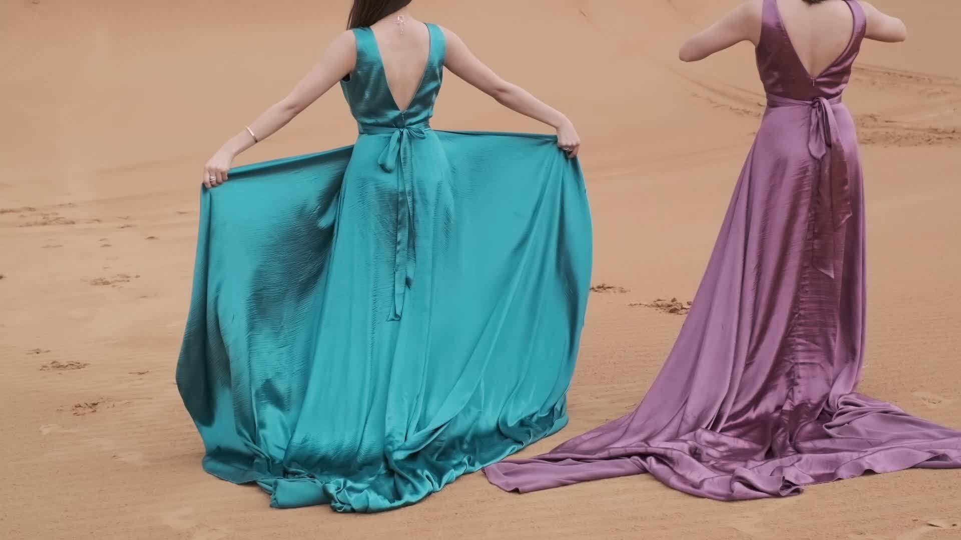 Two young women in long dresses developing in the wind stand barefoot ...