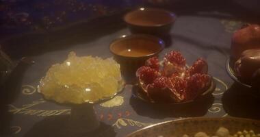 Oriental fruits and sweets on the table in a vase and on plates through a light curtain video