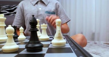 Boy wearing grey tee makes chess turn video