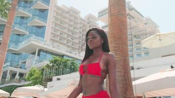 jovem moreno mulher dentro uma vermelho bikini e uma luz vestir caminhando descalço dentro uma privado piscina video