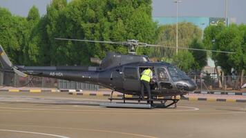 een jong brunette in een elegant zwart jurk krijgt uit van een klein privaat helikopter staand Bij de vliegveld video