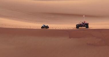 The drone flies over a group of ATVs standing on the desert sand video