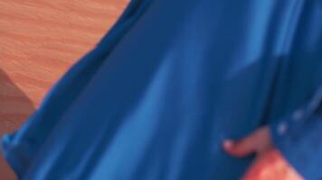 A young woman with flowing hair in a long blue dress walks barefoot through the desert dunes next to the sand-covered city. video