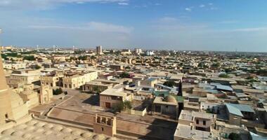 en Drönare flugor över de torn av ett gammal komplex kalyan minaret på en solig, molnig dag. gammal bukhara, uzbekistan. video