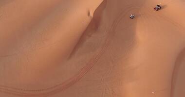 The drone flies over a group of ATVs standing on the desert sand video