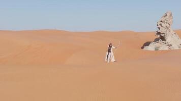 giovane barbuto uomo vestito come un' sciamano danza su deserto sabbia video
