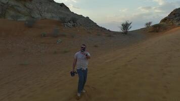 Drone shoots a man climbing a sand dune to a rock video