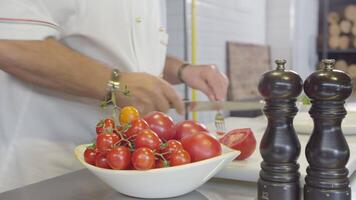 Chef cuts tomato on cutting board in slow motion video