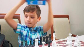 Boy in blue checkered shirt plays chess video