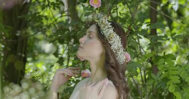 Woman with wreath of flowers stands in the garden video