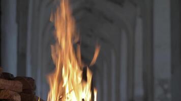 The feet of a man passing by a fire at night against the backdrop of an old Asian-style building video